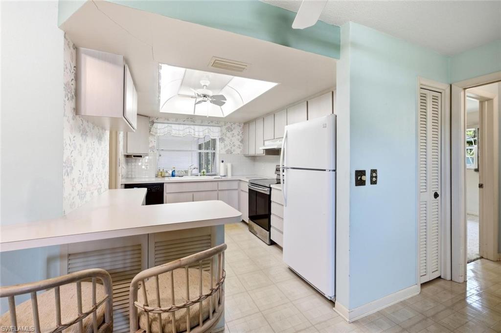 Kitchen featuring a skylight, white cabinetry, black countertops, and a breakfast bar