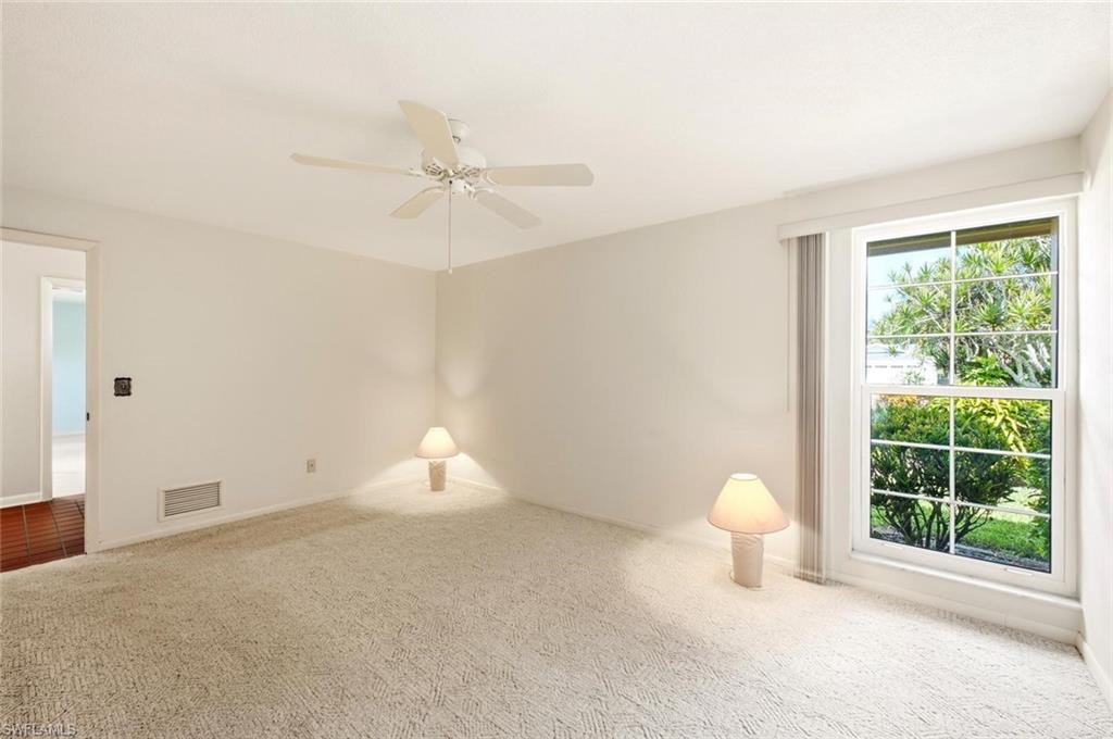 Carpeted room with a ceiling fan, a large window, and light-toned walls