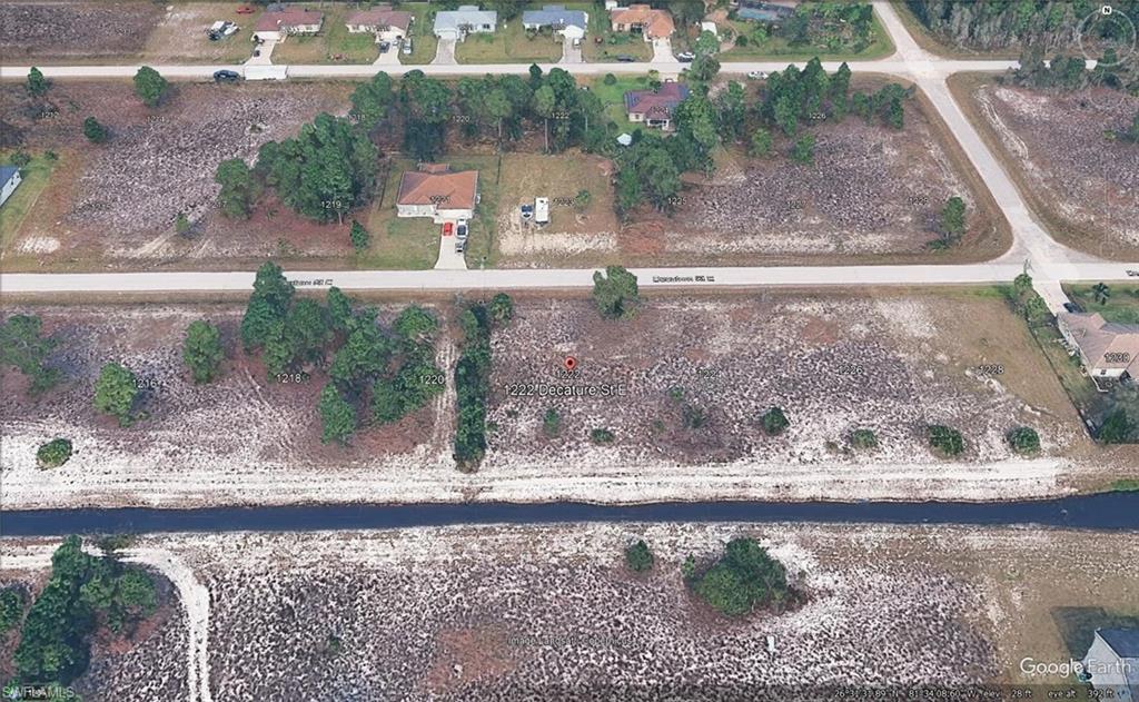 Expansive undeveloped land parcel featuring mature trees, direct road frontage, and a bordering canal