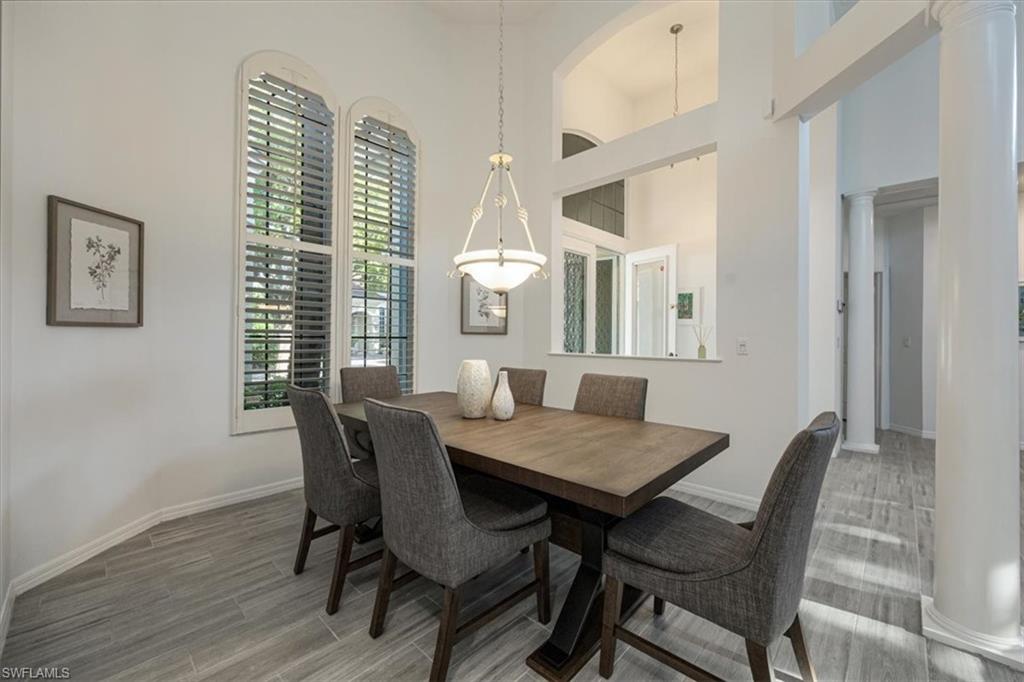 Dining area with wood finished floors, decorative columns, and a towering ceiling