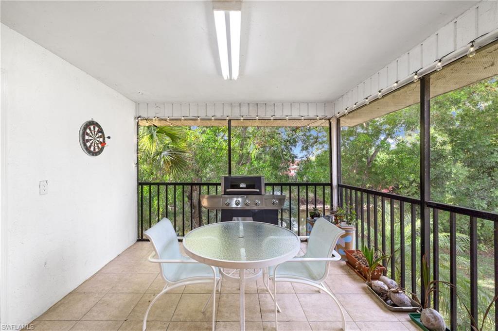 Screened balcony featuring tiled flooring, a white ceiling with a single light fixture, and black railings