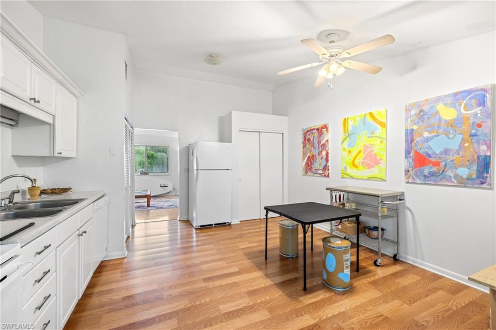 Kitchen with white cabinetry, white appliances, and wood-finish flooring