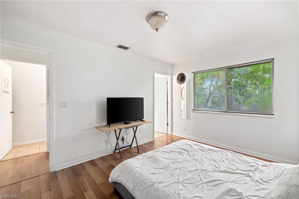 White painted walls, wood-finish flooring, two large windows, white ceiling, and an overhead flush-mount light fixture