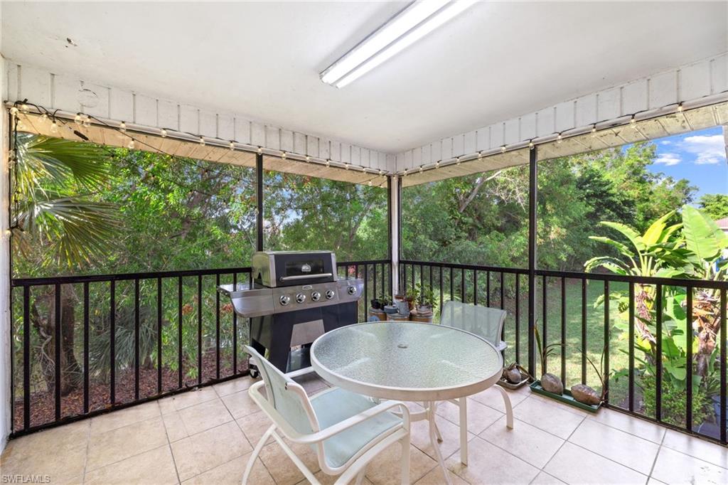 Screened-in patio with tile flooring, a built-in outdoor lighting fixture, and a black metal railing