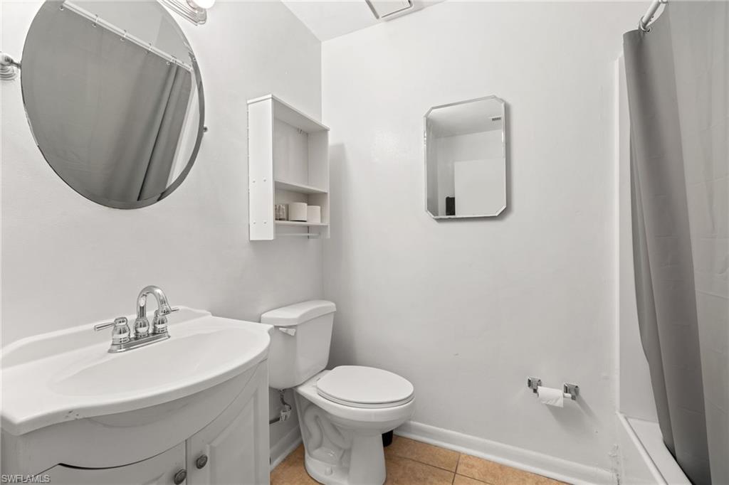 White vanity with integrated sink, chrome faucet, and round mirror