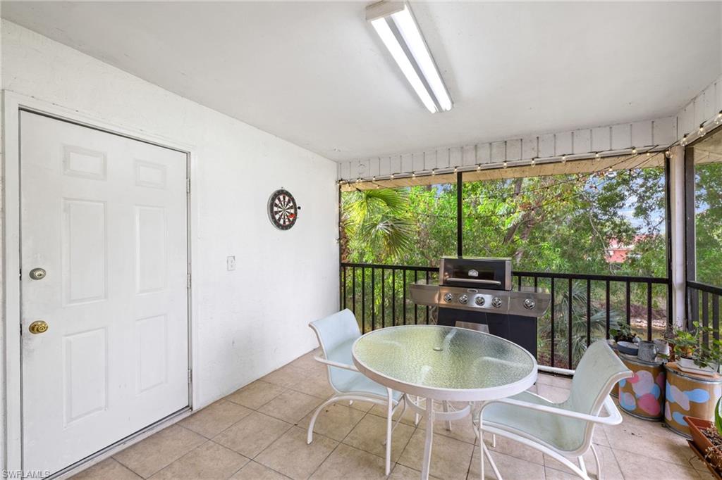 Screened porch with tiled flooring, white painted walls, and black metal railings