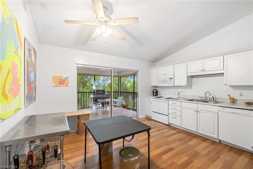 Vaulted ceiling with a ceiling fan, wood-finish flooring, white cabinetry, white appliances, and a screened balcony