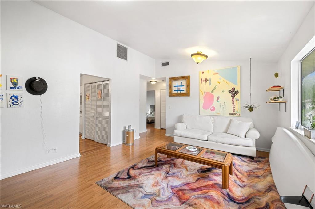 Wood-finish flooring, white walls, vaulted ceiling, recessed lighting, and a large window
