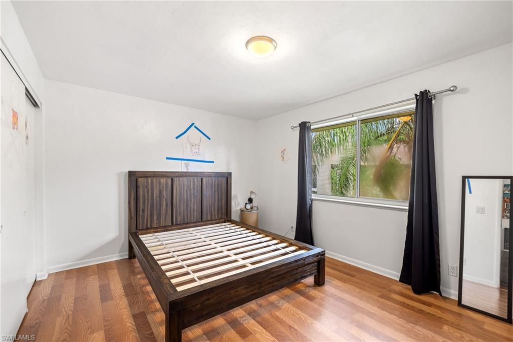 Hardwood flooring, window with natural lighting, ceiling-mounted light fixture, sliding closet door, and white wall finishes