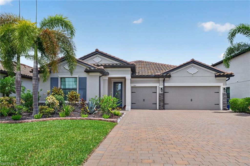 Single-story residence featuring a tile roof, stucco exterior, and a paver driveway