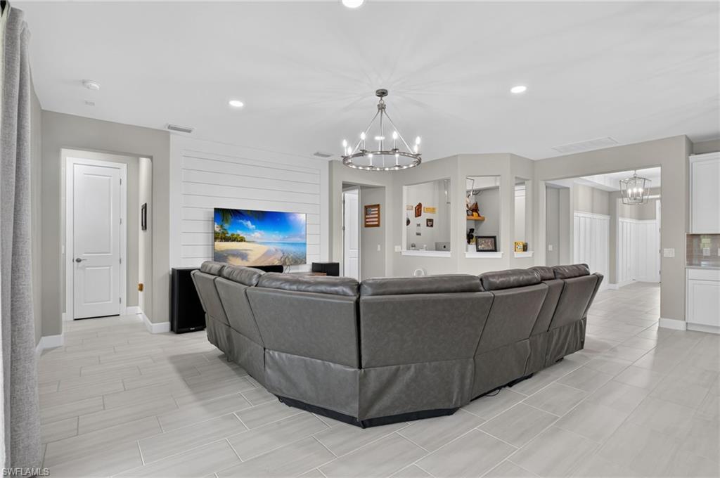 Spacious living area featuring light gray tile flooring, recessed lighting, and a shiplap accent wall