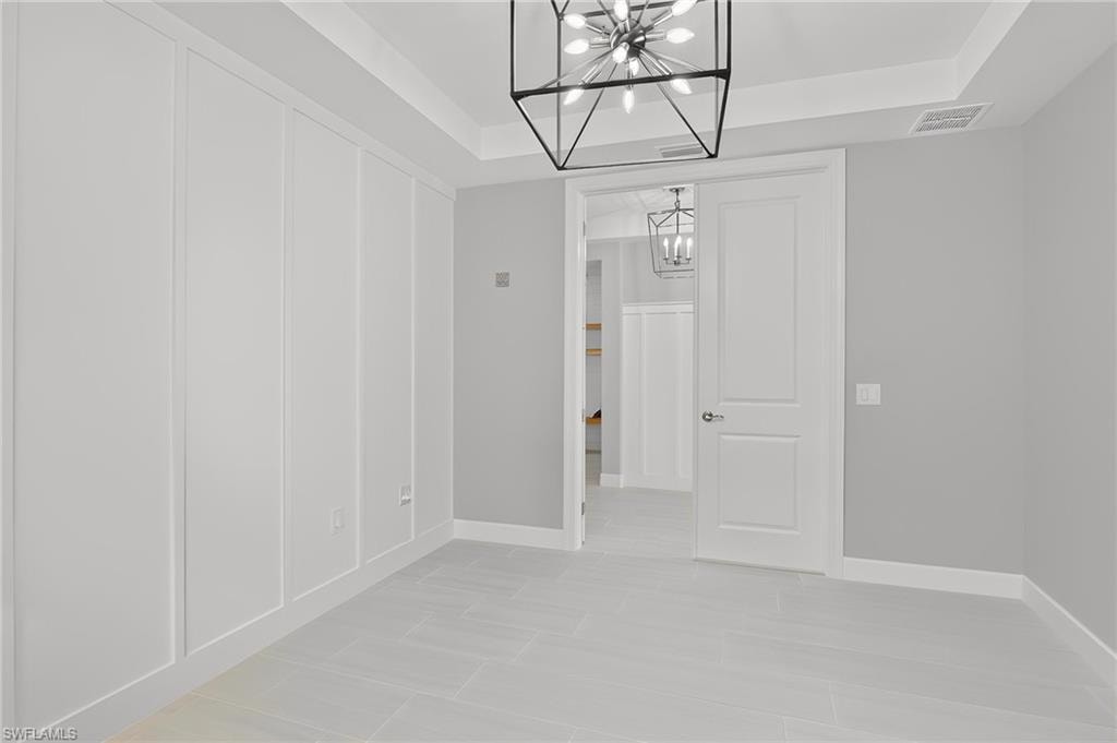 Interior space featuring plank wall paneling, a tray ceiling, and a modern geometric chandelier