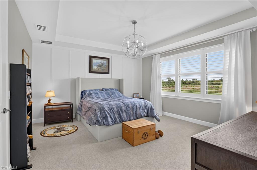 Spacious bedroom featuring a tray ceiling, recessed lighting, and a contemporary chandelier