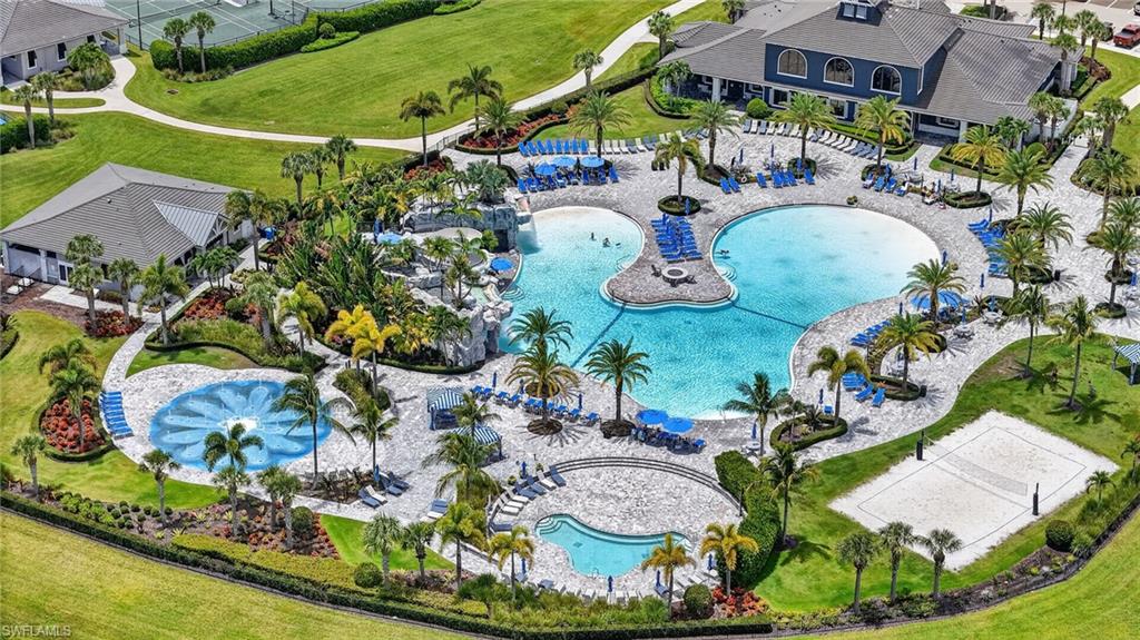 Expansive resort-style pool area featuring multiple swimming pools, a volleyball court, and lush landscaping