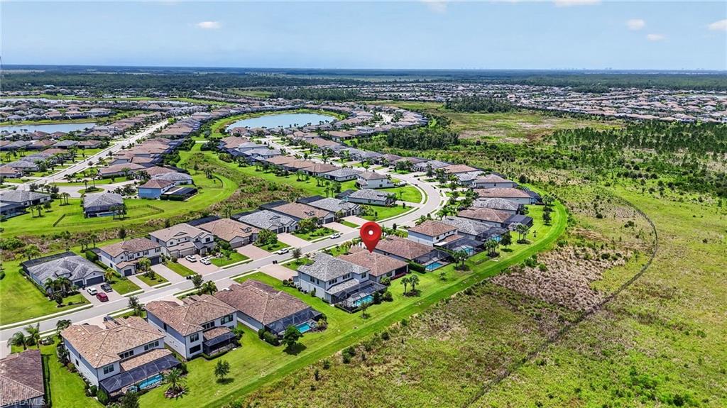 Aerial perspective of a developed residential community featuring single-family homes, landscaped yards, and a curved street layout