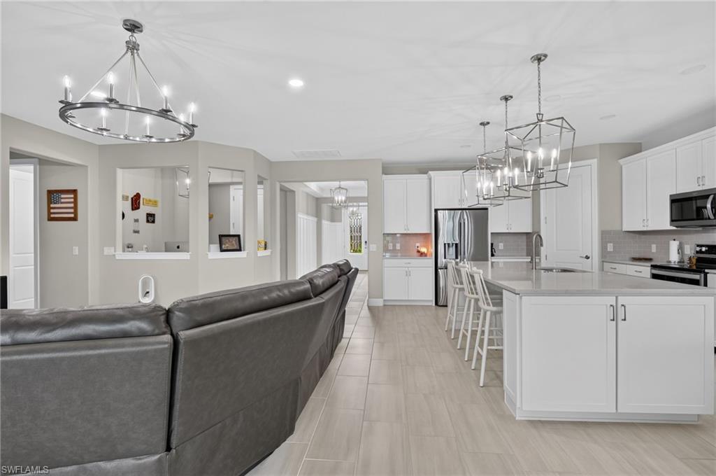 Open-concept living area featuring light wood-finish flooring, recessed lighting, and a contemporary chandelier