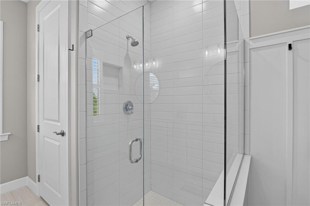 Glass-enclosed shower featuring white subway tile, a built-in shower niche, and a chrome showerhead