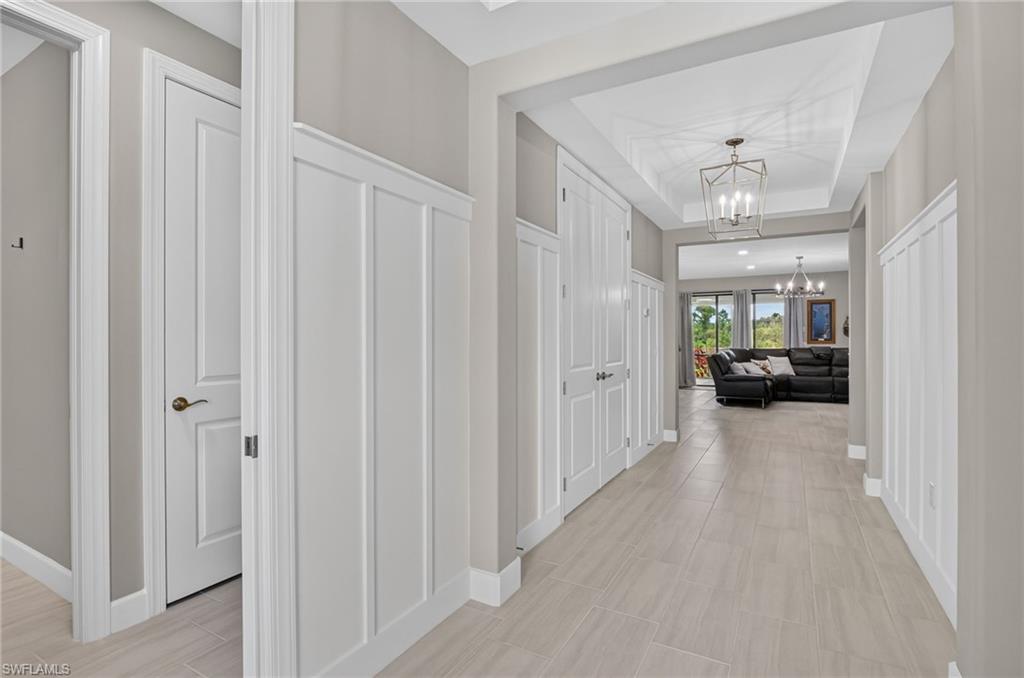 Hallway with light-toned tile flooring and tray ceiling