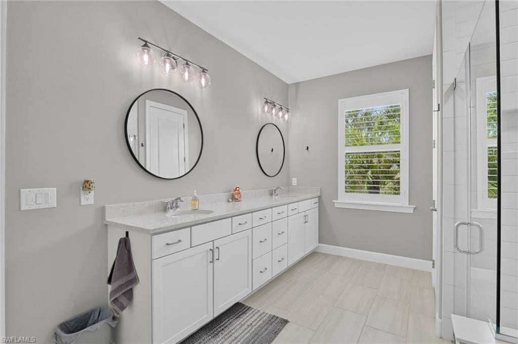 Dual vanity with white cabinetry, quartz countertops, and round black-framed mirrors