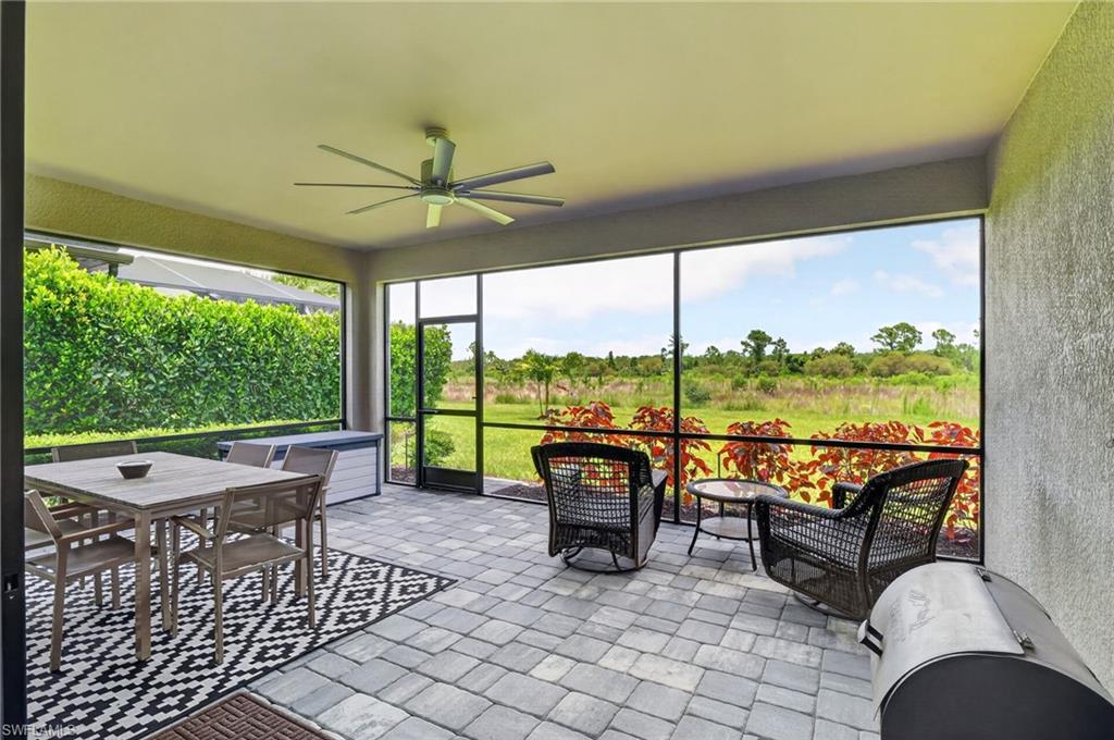 Screened outdoor living area featuring paver flooring, a ceiling fan, and direct access to the exterior