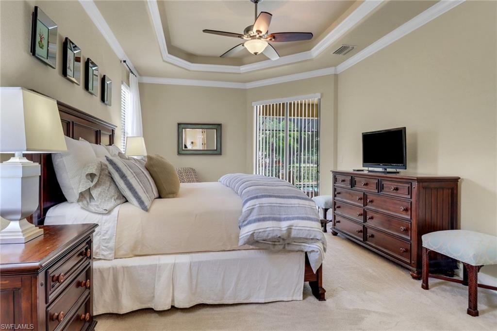 Bedroom with ornamental molding, a tray ceiling, light carpet, access to exterior, and ceiling fan