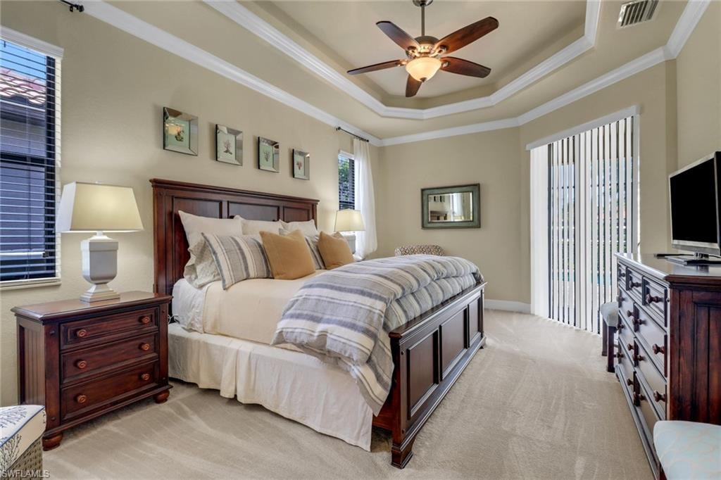 Bedroom featuring ornamental molding, light carpet, access to exterior, a raised ceiling, and ceiling fan