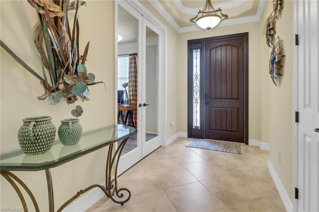 Foyer with ornamental molding, french doors, and light tile patterned floors