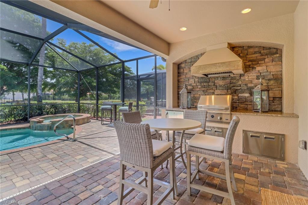View of patio / terrace with area for grilling, a lanai, ceiling fan, and a pool with connected hot tub