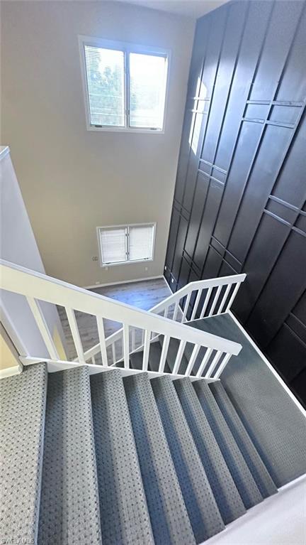 Two-story foyer featuring a textured accent wall, white balusters, and a carpeted staircase