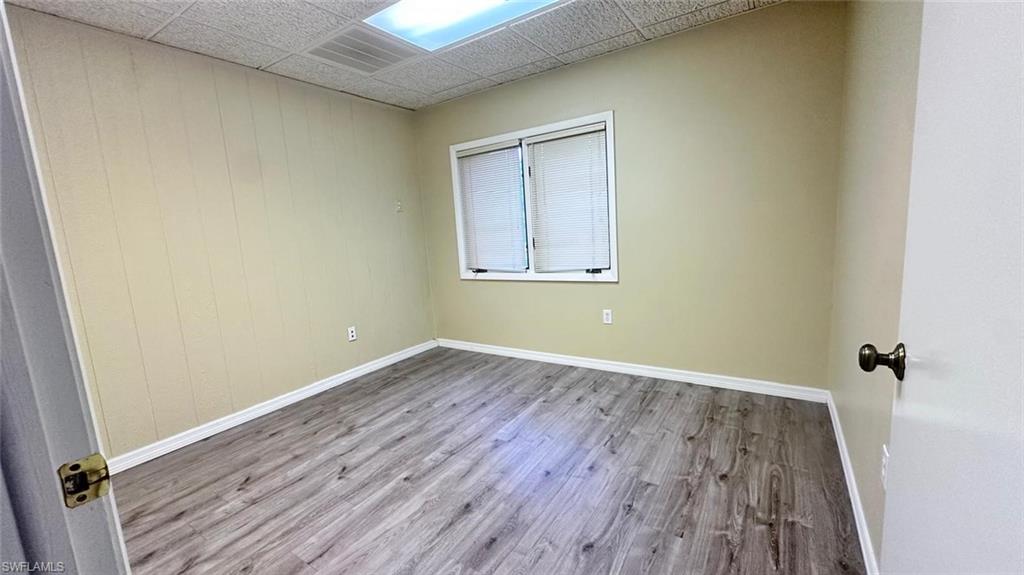 Room featuring wood-finish flooring and a drop ceiling with integrated lighting