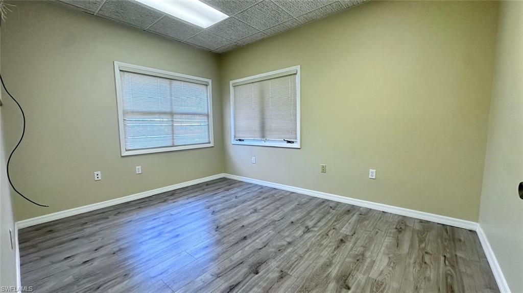 Room featuring wood-finish flooring, two windows with blinds, recessed lighting, and neutral wall tones