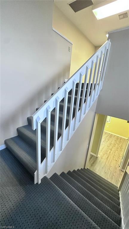 Carpeted stairway with white painted railing, neutral wall tones, and recessed lighting