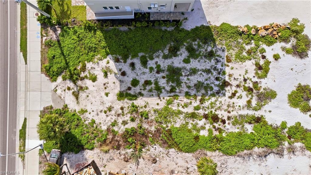 Expansive undeveloped lot featuring sandy terrain and natural vegetation, offering significant ground for development - Virtually Edited Image