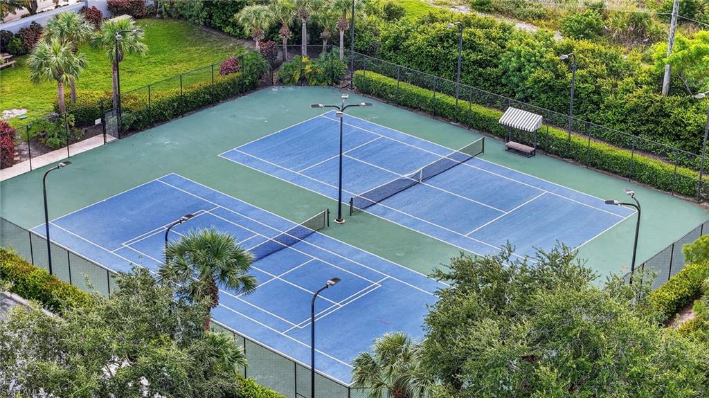 Two tennis courts with blue and green surfacing, black netting, and surrounding fencing