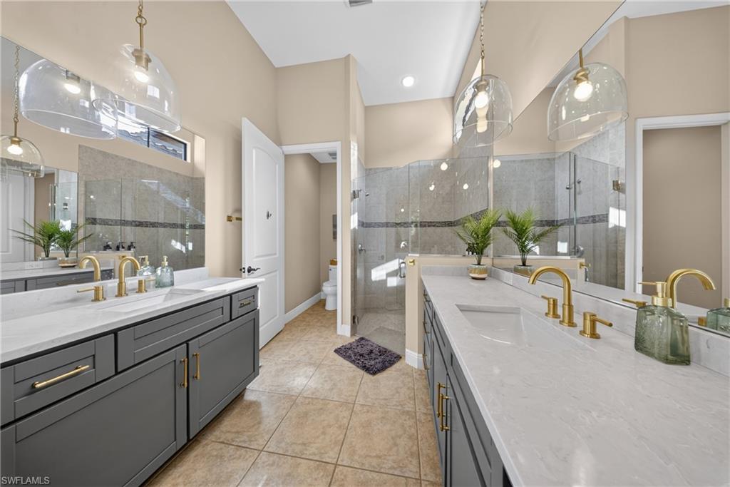 Dual vanities featuring gray cabinetry, integrated sinks, and gold-finish fixtures