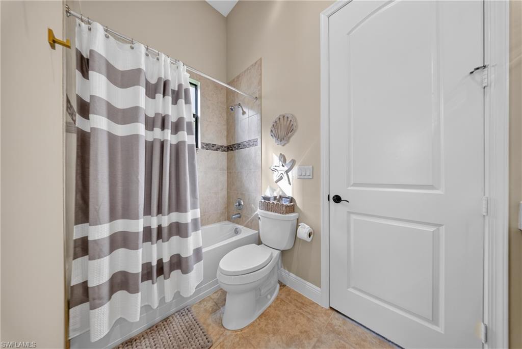 Full bathroom featuring a tiled shower with a decorative accent band and a compact window