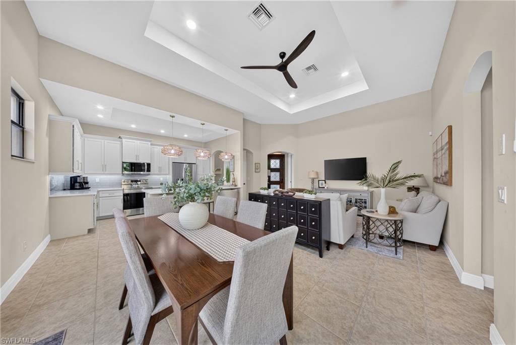 Open-concept living space with a tray ceiling and contemporary ceiling fan