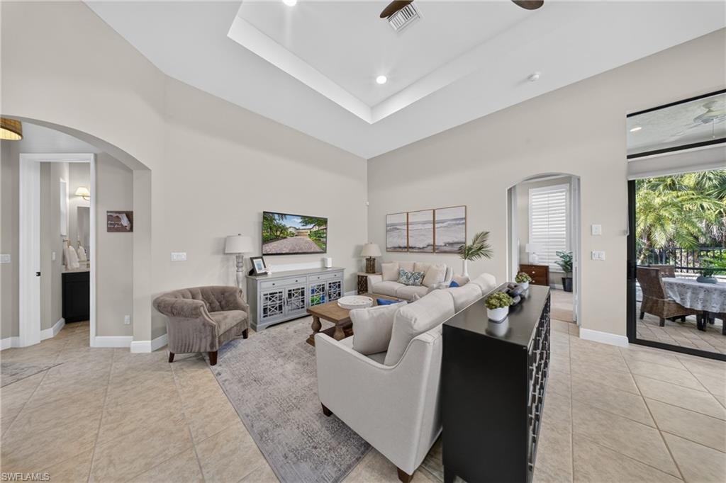 Spacious living area featuring tile flooring, vaulted ceilings with recessed lighting, and a neutral color palette