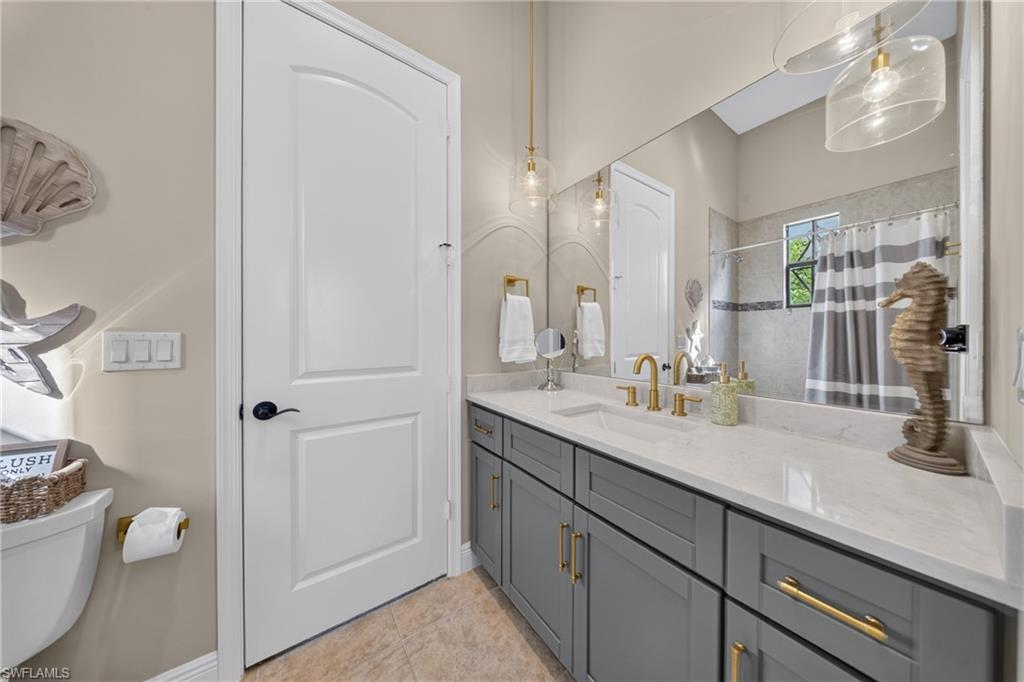 Bathroom featuring a gray vanity with gold hardware, a white countertop, and dual pendant lighting fixtures