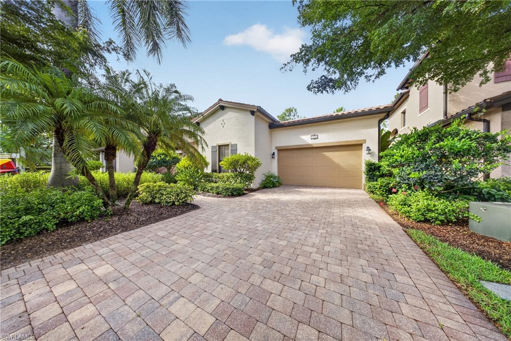 Stucco exterior home featuring a terracotta-style tile roof and an integrated garage