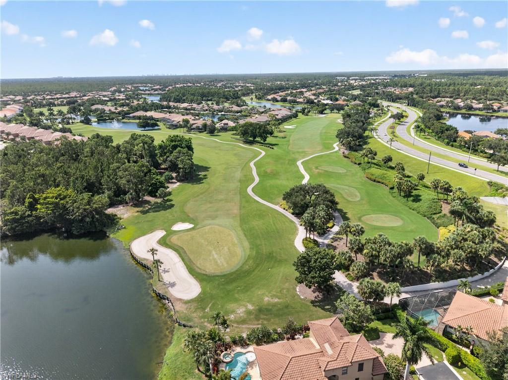 Golf course fairway and green with sand bunkers, bordered by a large pond and mature trees