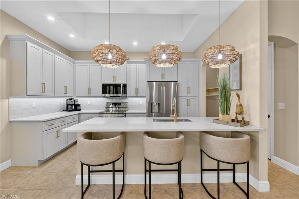 Modern kitchen featuring light gray shaker cabinetry, white subway tile backsplash, and white countertops