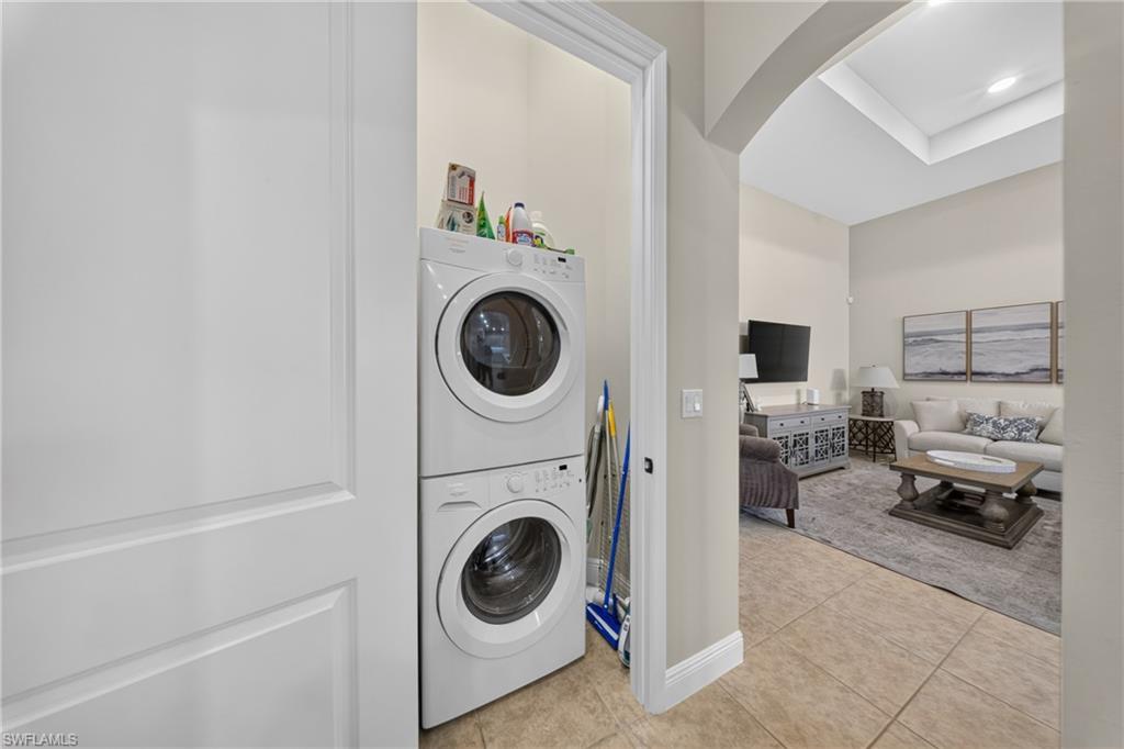 Convenient laundry alcove featuring stacked appliances and tile flooring