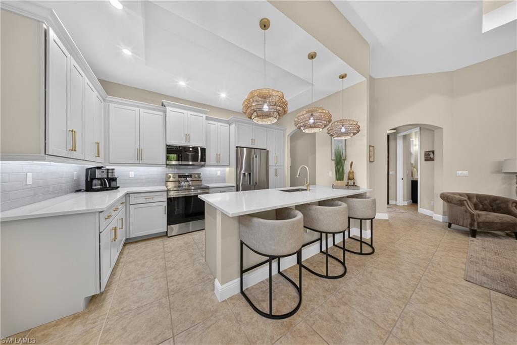 Modern kitchen featuring white shaker cabinetry, stainless steel appliances, a white subway tile backsplash, and light-toned flooring