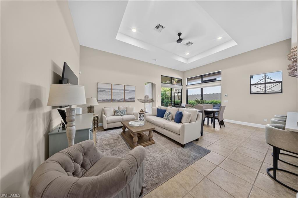 Spacious interior featuring a coffered ceiling with recessed lighting and a ceiling fan, tile flooring, and large windows with transom details