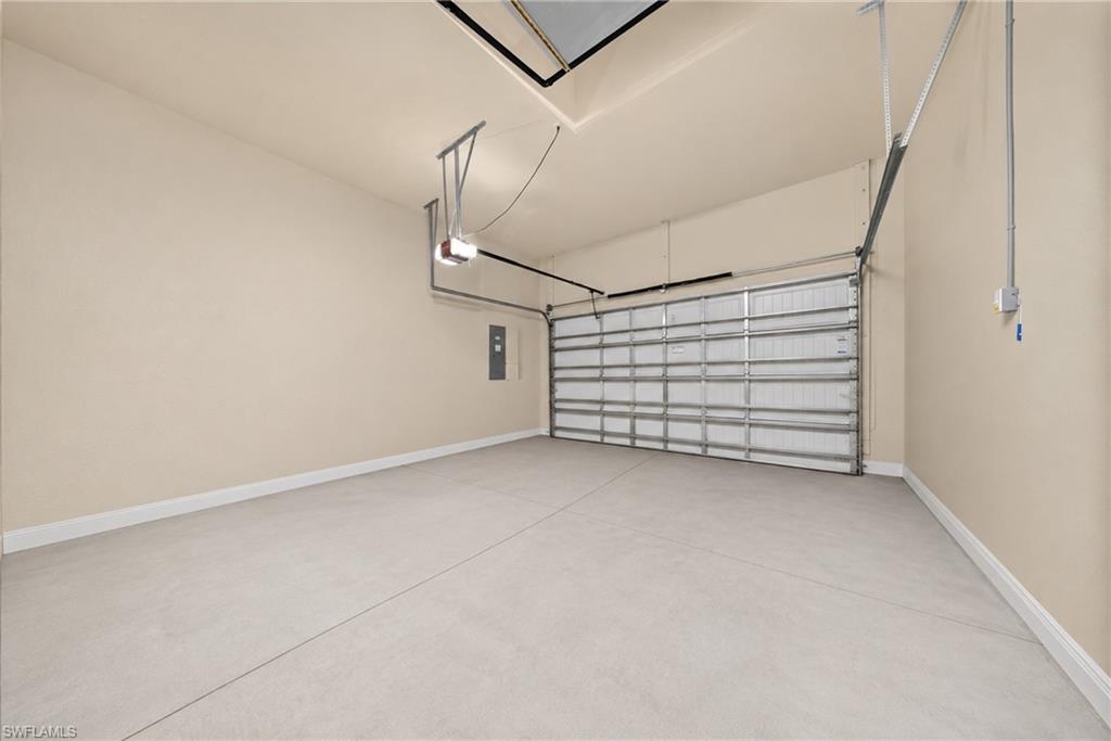 Spacious two-car garage featuring a sectional garage door with automatic opener, neutral painted walls, and concrete flooring