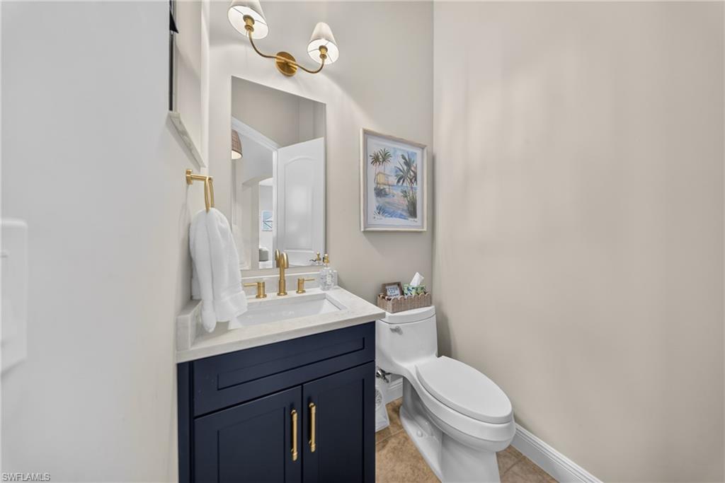 Powder room featuring a navy vanity with gold hardware, white countertop, and gold-finish faucet