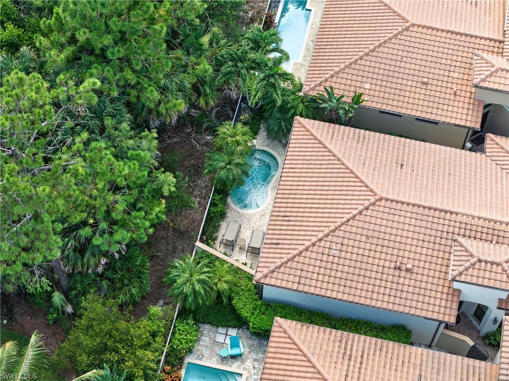 Aerial perspective showcasing multiple homes with terracotta-style tile roofs, private swimming pools, and extensive surrounding tropical foliage