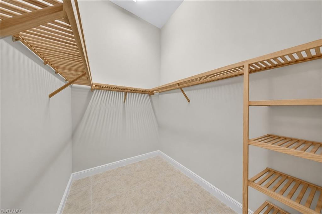 Walk-in closet featuring light wood shelving and hanging rods