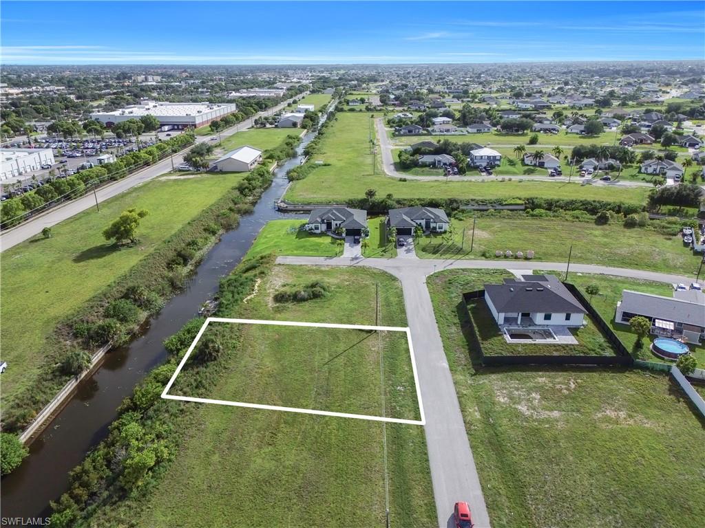 Expansive cleared lot bordered by a waterway, featuring street frontage and surrounding development